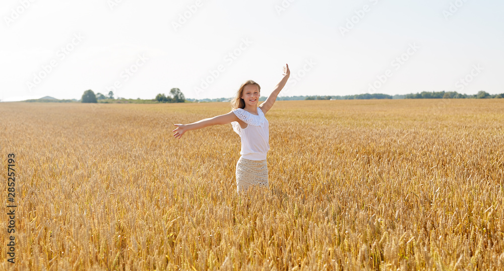 nature, harvest and freedom concept - happy young girl with hands outstretched on cereal field in summer nature, harvest and freedom concept - happy young girl with hands outstretched on cereal field in summer