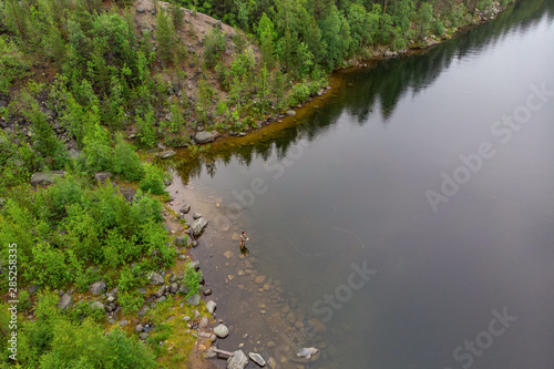 Fisherman man casts rod in mountain river in boots fly fishing salmon, morning. Aerial top view