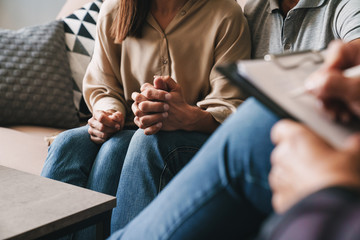 Cropped photo of casual caucasian couple having conversation with psychologist on therapy session in room
