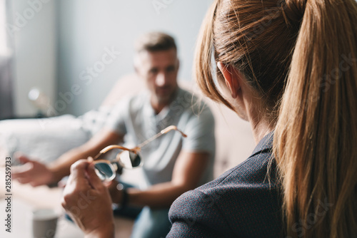 Photo of puzzled handsome man having conversation with psychologist in room