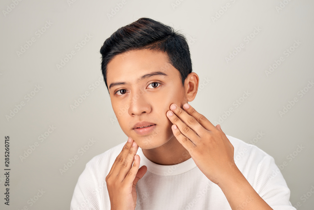 Portrait of shirtless young handsome Asian man checking his face for skin care and beauty concepts Portrait of shirtless young handsome Asian man checking his face for skin care and beauty concepts