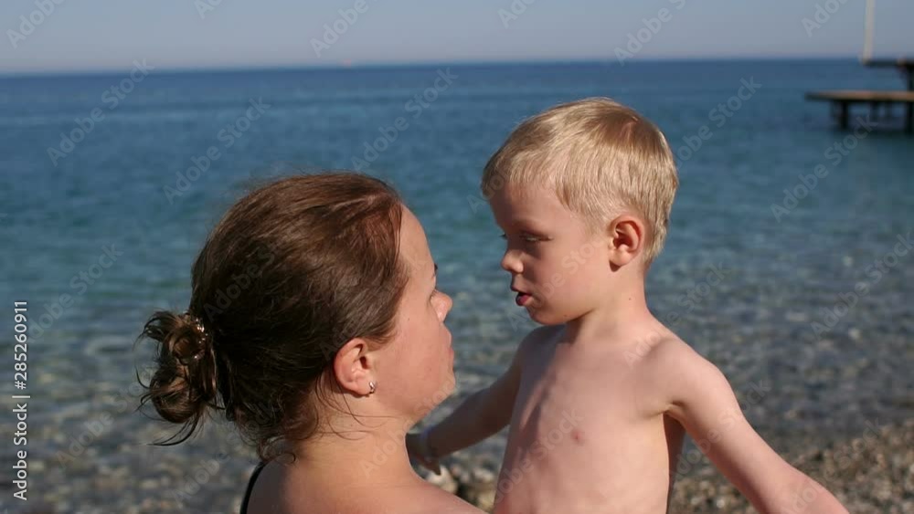 Young woman and her pretty little son are hugging and smiling on the tropical beach. Summer vacation, happy family, love concept. Slow motion. Young woman and her pretty little son are hugging and smiling on the tropical beach. Summer vacation, happy family, love concept. Slow motion.