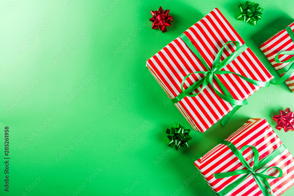 Fototapeta premium Christmas gift boxes simple pattern background. Festive boxes with Christmas presents, decorated with bright bows with ribbons. Flatlay, above copy space