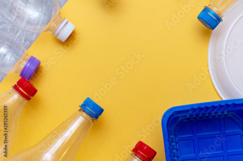 used plastic, crumpled empty bottles, packets, dish, container pollution garbage recycle eco concept yellow background close up