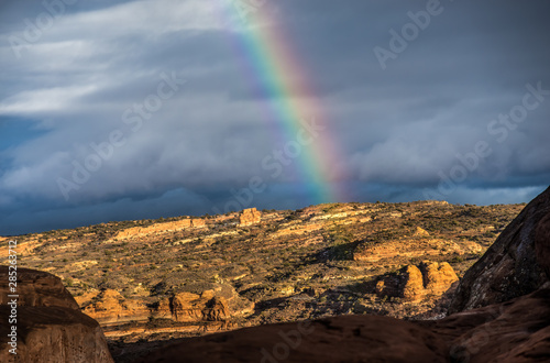 Rainbow Rises Above Sandstone Rocks with Dark Clouds Behind It