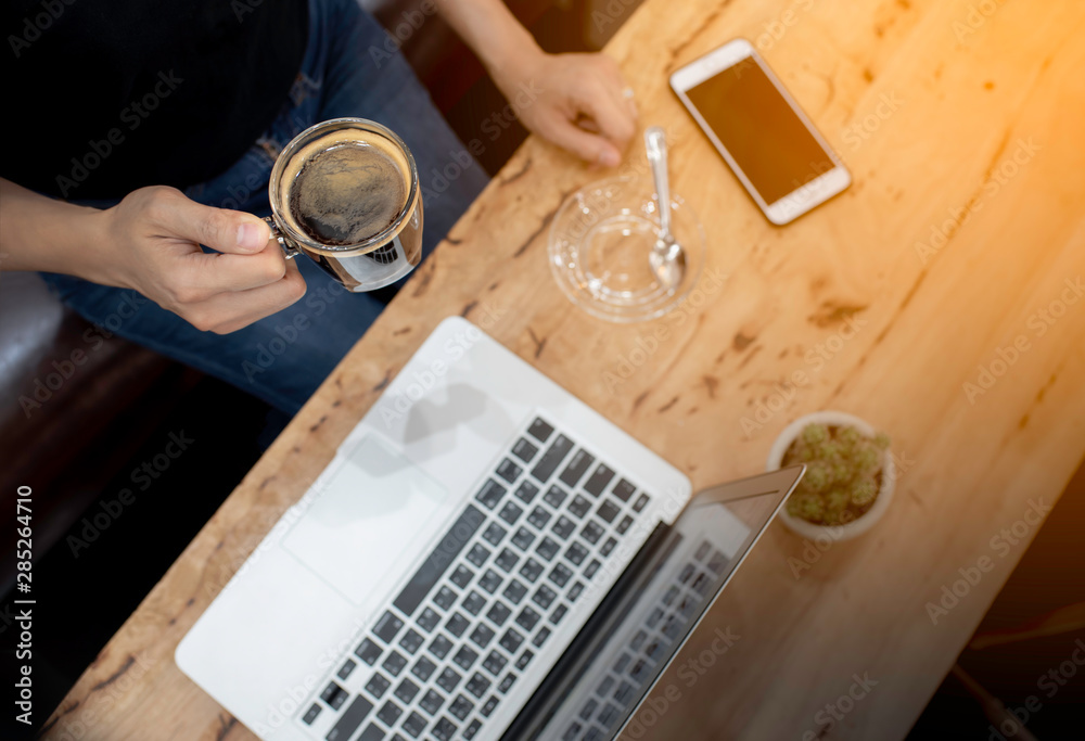 © rawin - Top view women working with smartphone and notebook ,her hand holding hot coffee