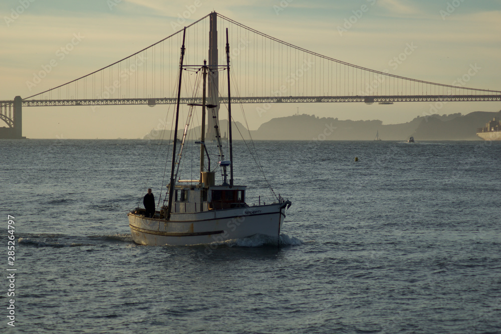 SAN FRANCISCO, CALIFORNIA, UNITED STATES - NOV 25th, 2018: Boat in San Francisco Bay with Golden Gate Bridge in the background during sunset