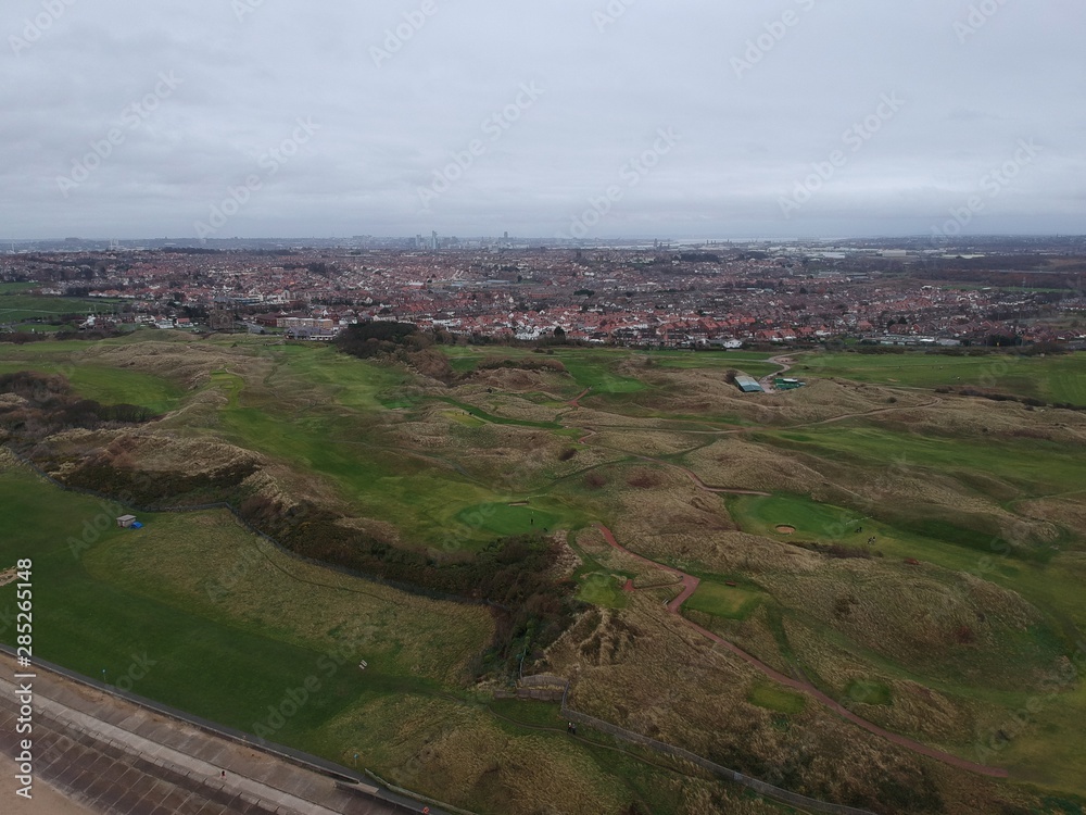 Obraz premium aerial view of hilly golf course with a city background