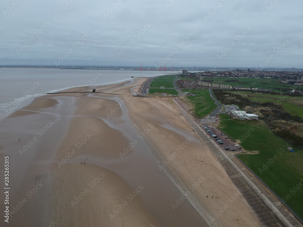aerial view of empty sandy beach with a port in background 