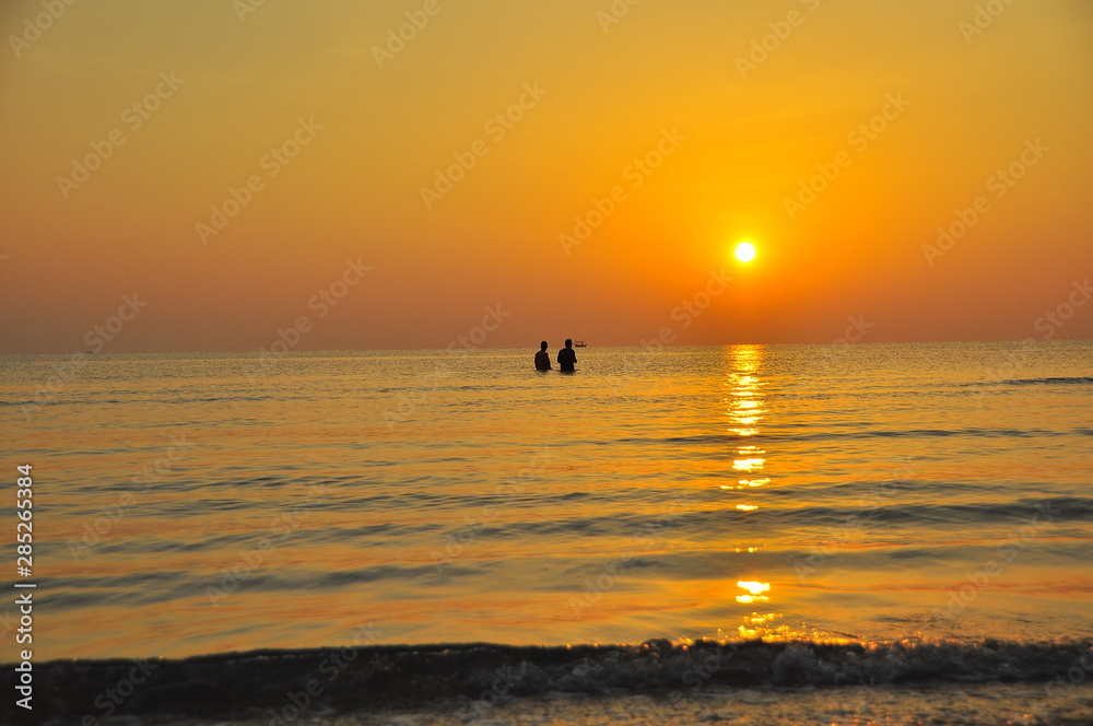 two man standing in sea ,sunset at the sea