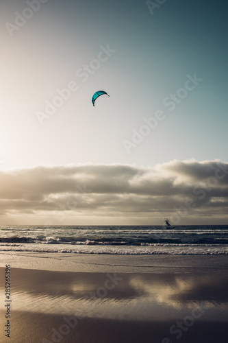 Personas practicando kitesurf al atardecer en la playa de Famara en la isla de Lanzarote