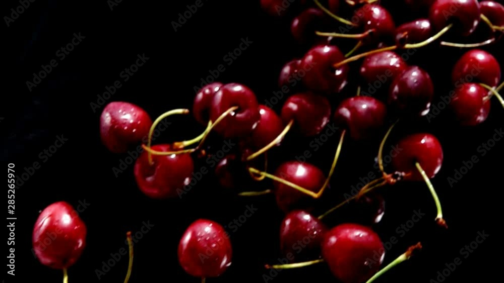 Rpe cherries fly on a black background closeup in slow motion Rpe cherries fly on a black background closeup in slow motion