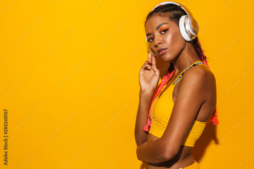 Image of athletic african american woman wearing afro braids listening to music with headphones - obrazy, fototapety, plakaty 