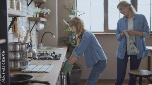 little girl helps mom bake cookies in the kitchen. girl takes out cookies with chocolate from the oven using kitchen potholders 4K