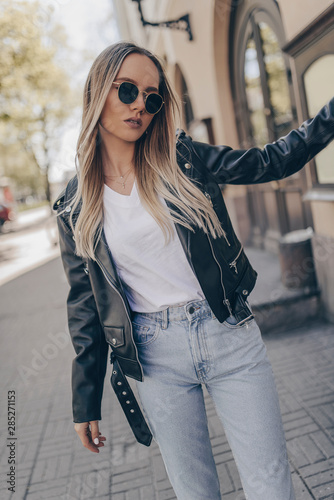 Stylish pretty woman posing in the street, wearing sunglasses. photo