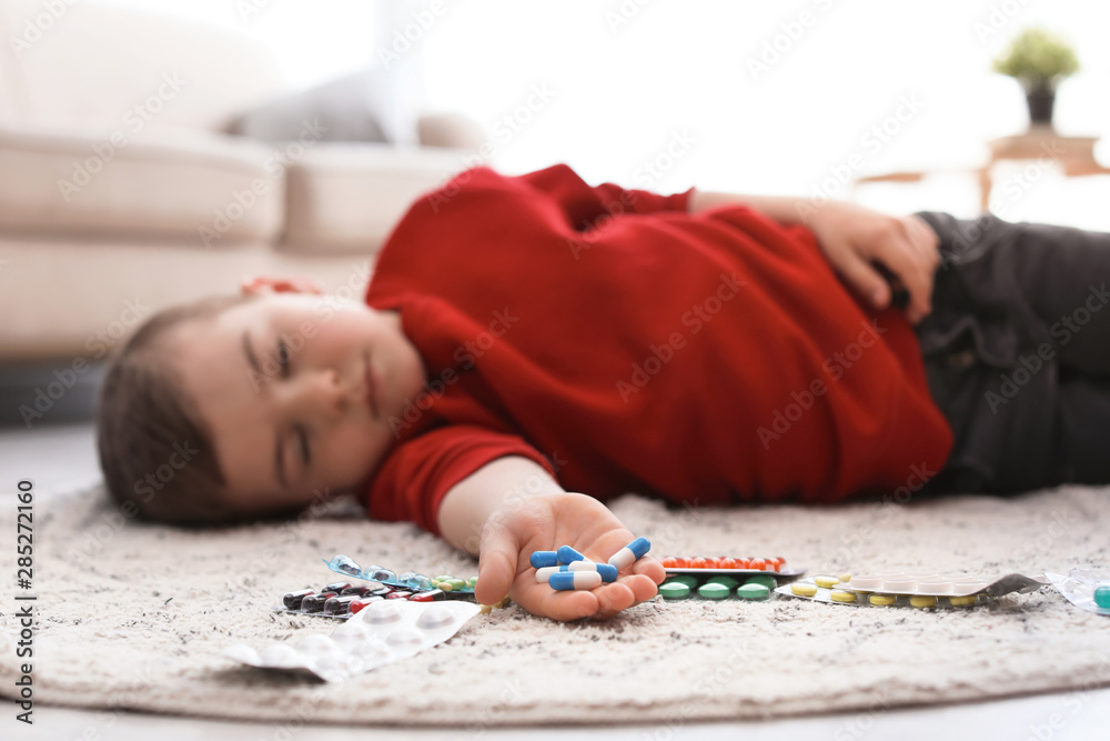 Unconscious little child with pills lying on floor at home. Household danger Unconscious little child with pills lying on floor at home. Household danger