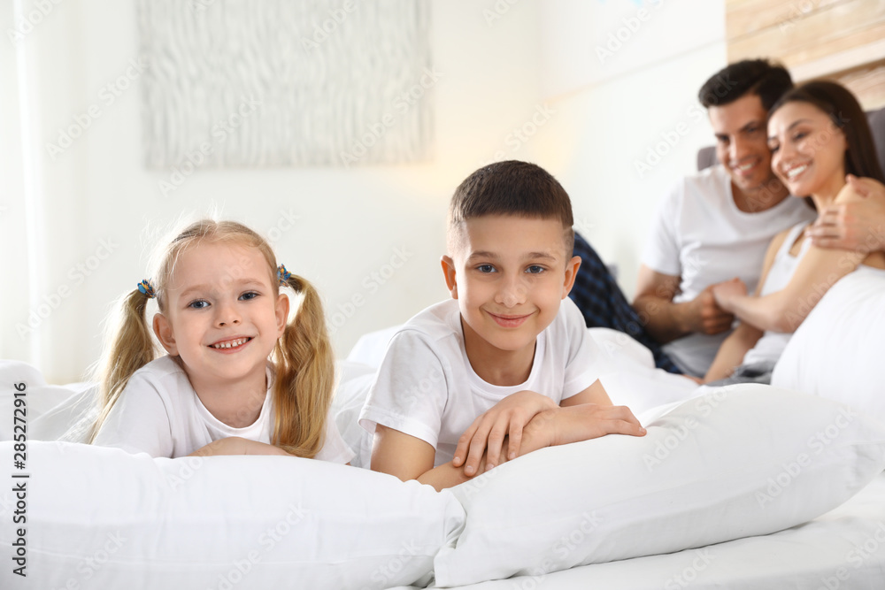 Cute happy children and their parents on large bed Cute happy children and their parents on large bed