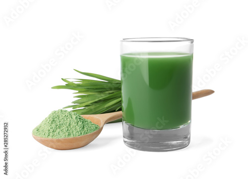 Glass of wheat grass juice, spoon with powder and sprouts on white background