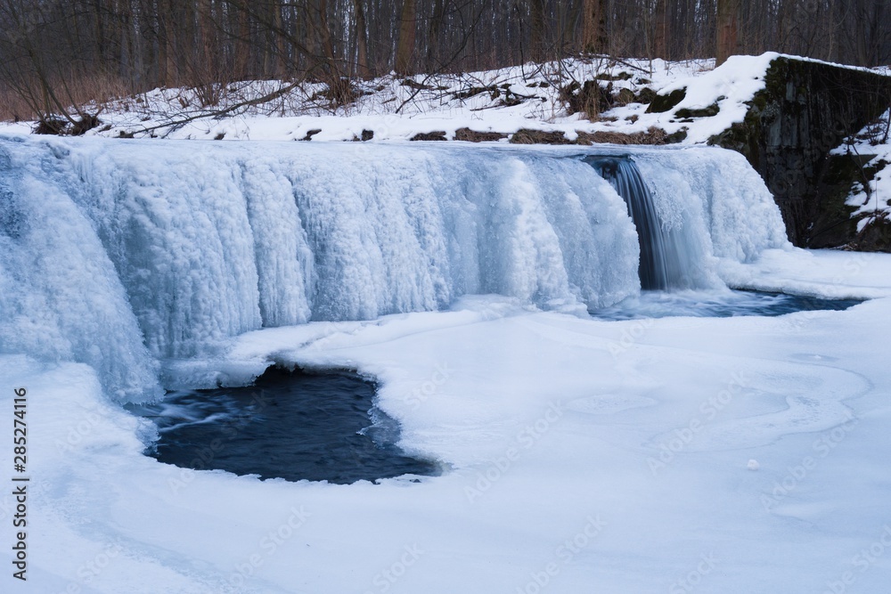 Fototapeta premium Frozen river, old water weir in winter. Ice beauty, frozen streams of water. Hluchova river, Bystrice, Czech republic.