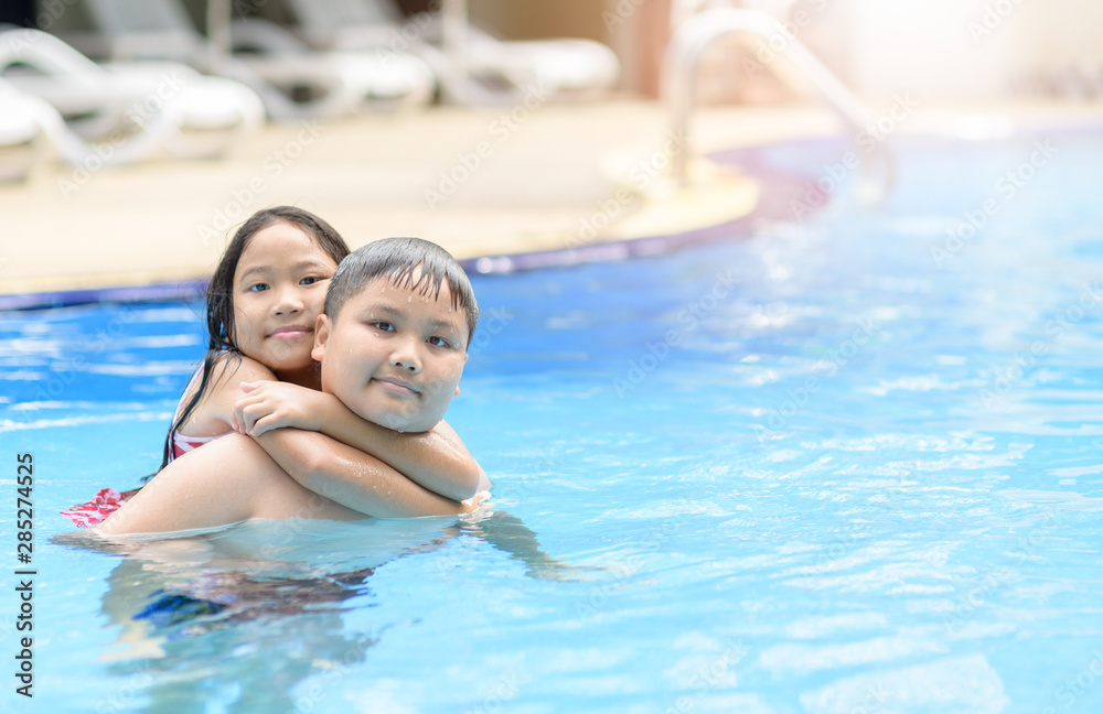 Brother and sister play water in swimming pool