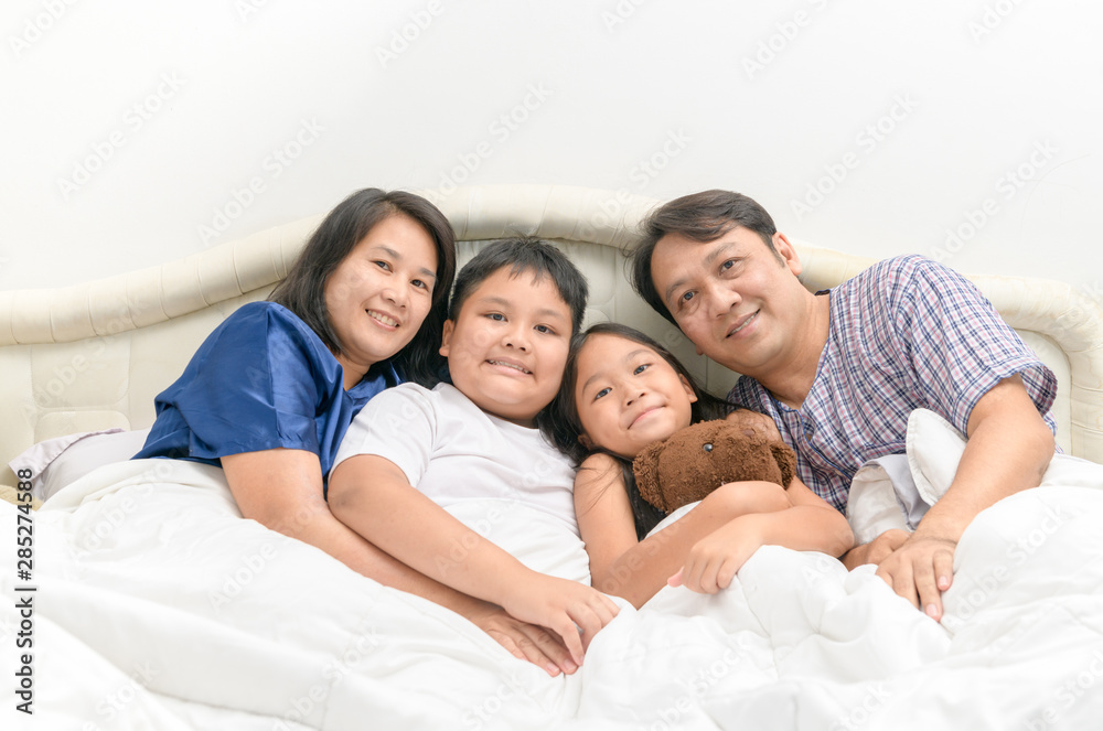 Happy Asian family lying and smile on a bed