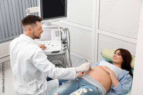 Young pregnant woman undergoing ultrasound scan in modern clinic photo