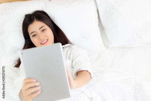 Attractive beautiful woman use tablet for communicating with friends, family on bed. Charming beautiful young woman is enjoying and satisfying high speed internet by broadband internet. copy space
