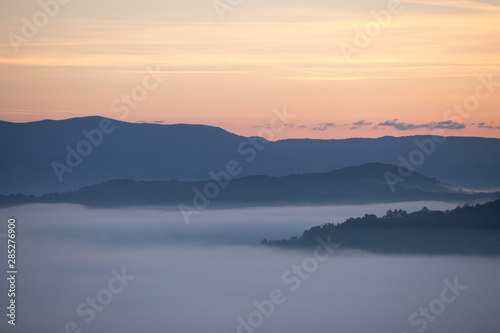 view of sunrise over the mountains mist and clouds under peaks