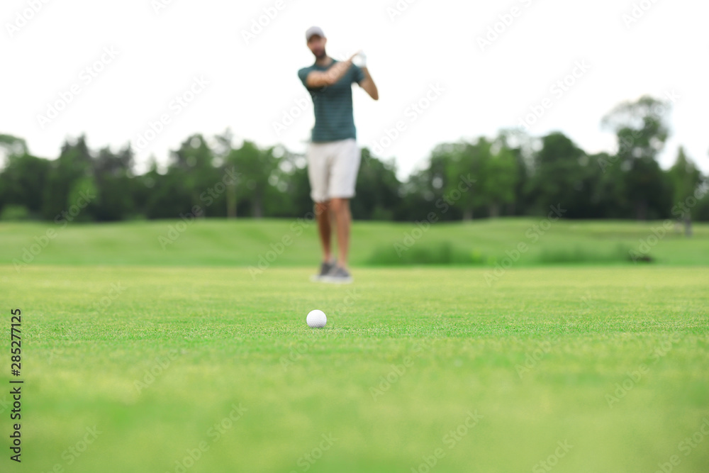 Man playing golf on green course, ball in focus. Sport and leisure Man playing golf on green course, ball in focus. Sport and leisure