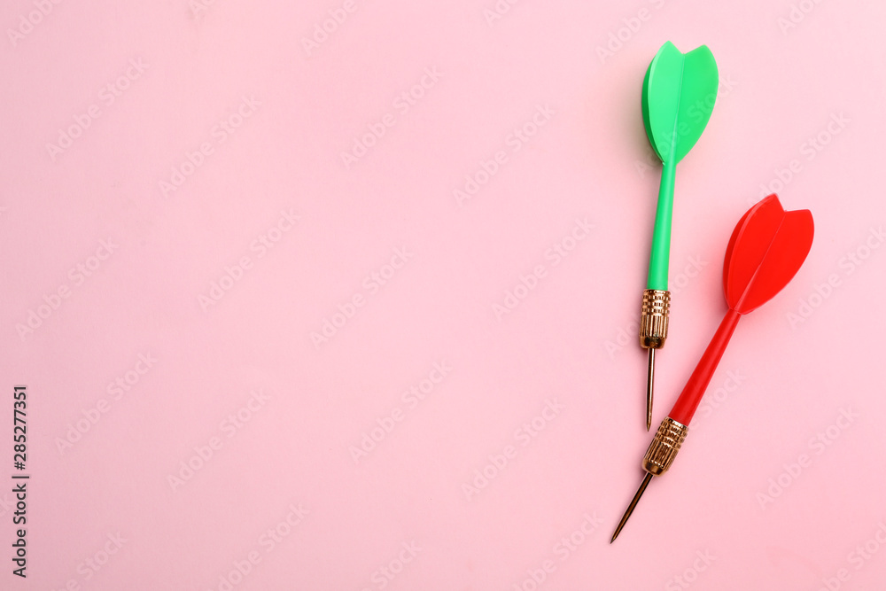 Plastic dart arrows on pink background, flat lay with space for text Plastic dart arrows on pink background, flat lay with space for text