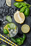 Summer basil lemonade on grey background. Fresh summer cocktail with basil, lemon and ice cubes. Homemade fresh lemonade with lemon and basil. Food and drink concept