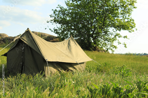 Camping tent in green field on sunny day. Space for text