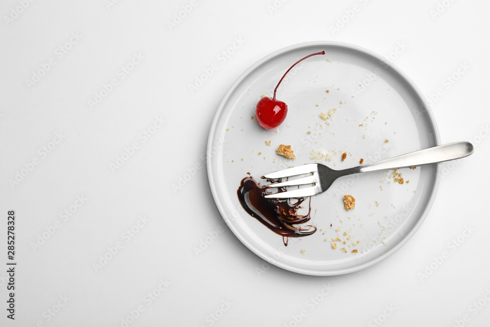 Dirty plate with food leftovers, fork and canned cherry on white background, top view Dirty plate with food leftovers, fork and canned cherry on white background, top view