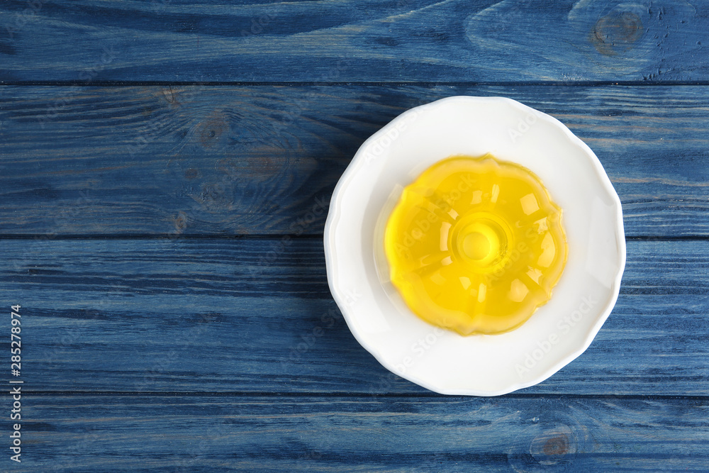 Plate with tasty fruit jelly on blue wooden table, top view. Space for text Plate with tasty fruit jelly on blue wooden table, top view. Space for text