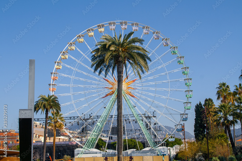 Fair Ferris Wheel behind a big palm tree Fair Ferris Wheel behind a big palm tree