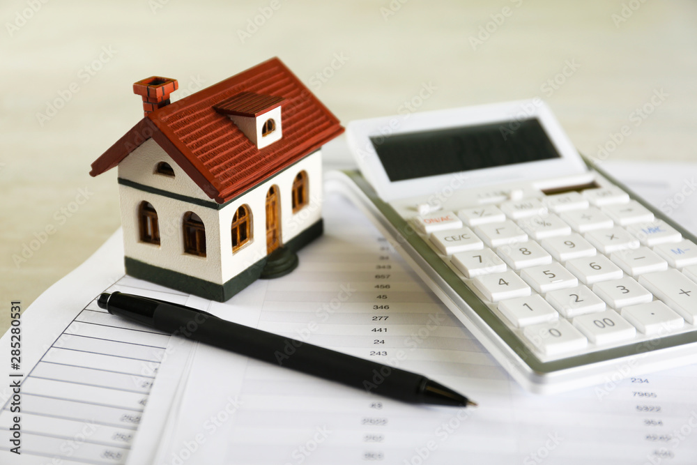 Calculator, house model, pen and documents on light table. Real estate agent's workplace Calculator, house model, pen and documents on light table. Real estate agent's workplace