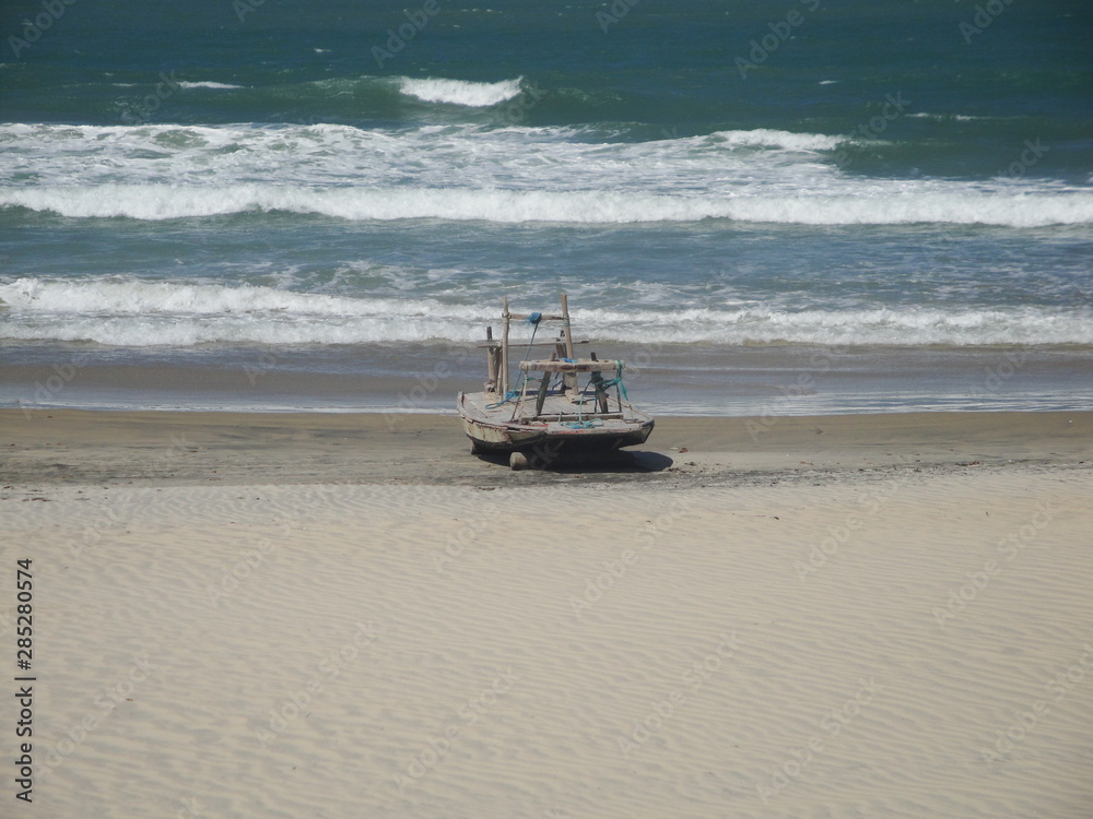 Beautiful view of a boat in the sand with the sea in the background on a beach of Ceara, Brazil.