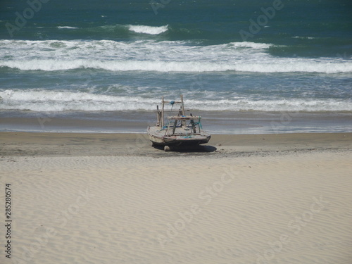 Beautiful view of a boat in the sand with the sea in the background on a beach of Ceara, Brazil.