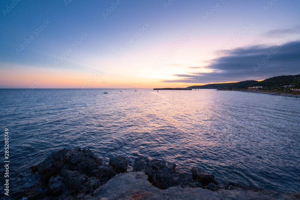 Beach of Sant Tomas on the island of Menorca during sunset. Mediterranean sea in spanish island. Beach of Sant Tomas on the island of Menorca during sunset. Mediterranean sea in spanish island.