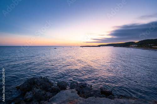 Beach of Sant Tomas on the island of Menorca during sunset. Mediterranean sea in spanish island.