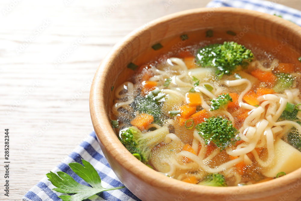 Bowl of fresh homemade vegetable soup on wooden background, closeup