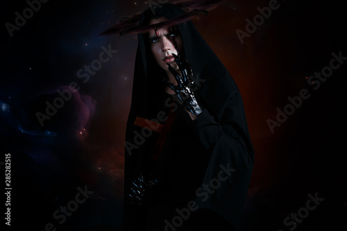 Evil demon with a nimb and cross with black glossy hands and big claws. Standing in black robe on a space background