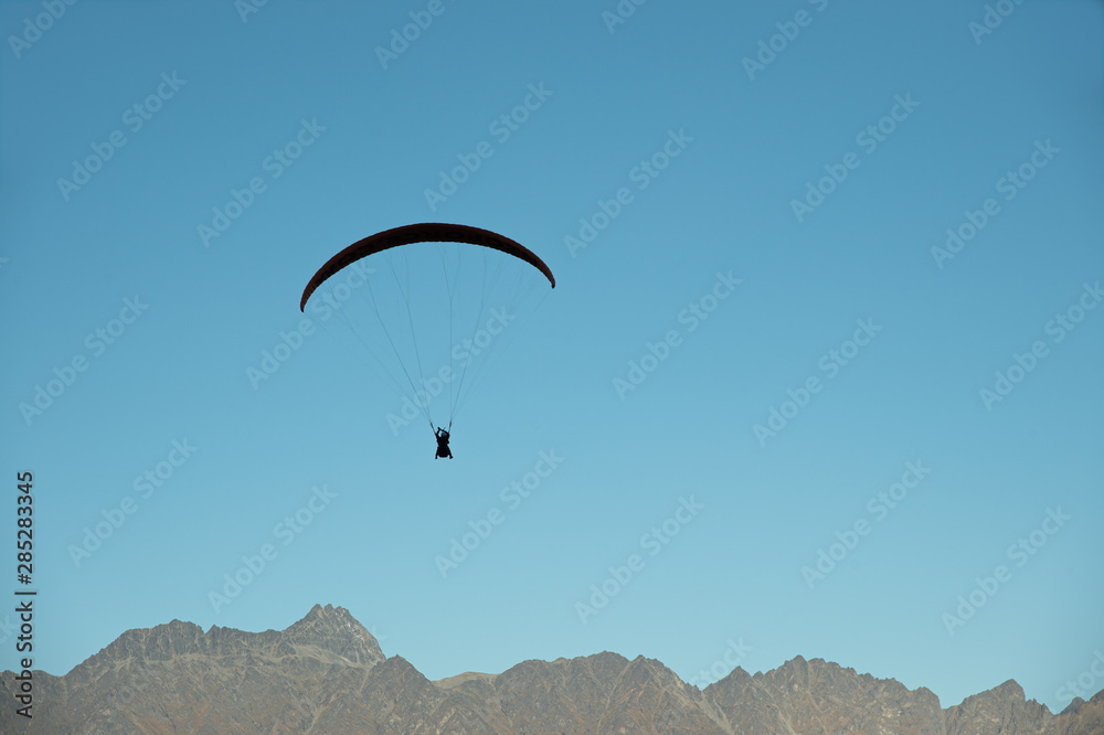 Paragliding on beautiful clear blue sky over mountain, most popular extreme sport in Queenstown, New Zealand. Paragliding on beautiful clear blue sky over mountain, most popular extreme sport in Queenstown, New Zealand.