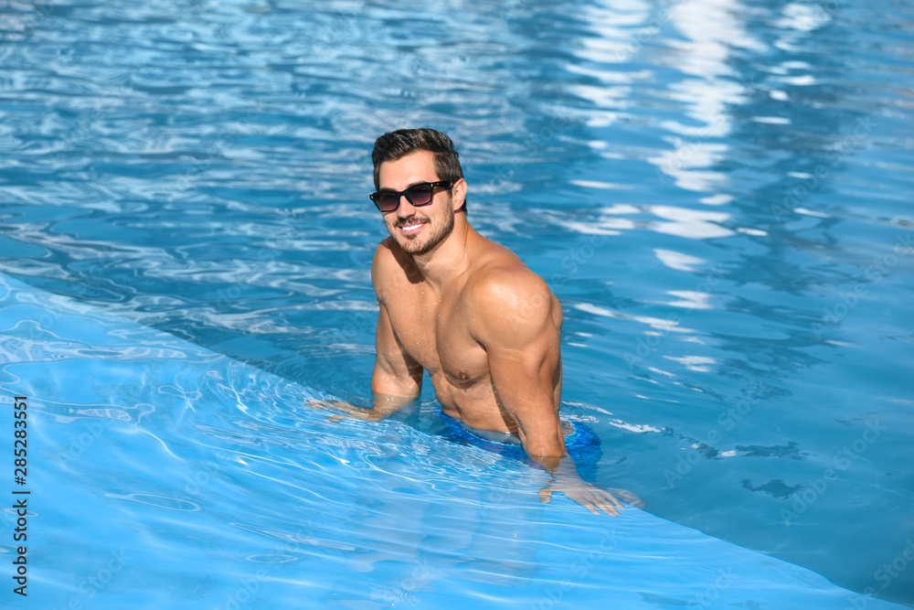 Handsome young man in swimming pool on sunny day