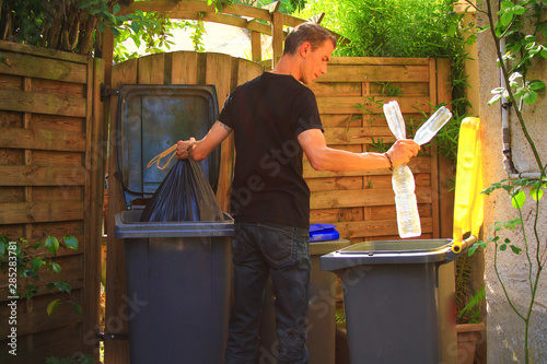 фотографія View on profil of one person performing a selective sorting of household waste in recycling bins