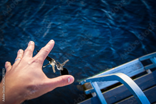 Man dropping his keys to the bottom of the sea. Trying to reach them before they sink underwater.