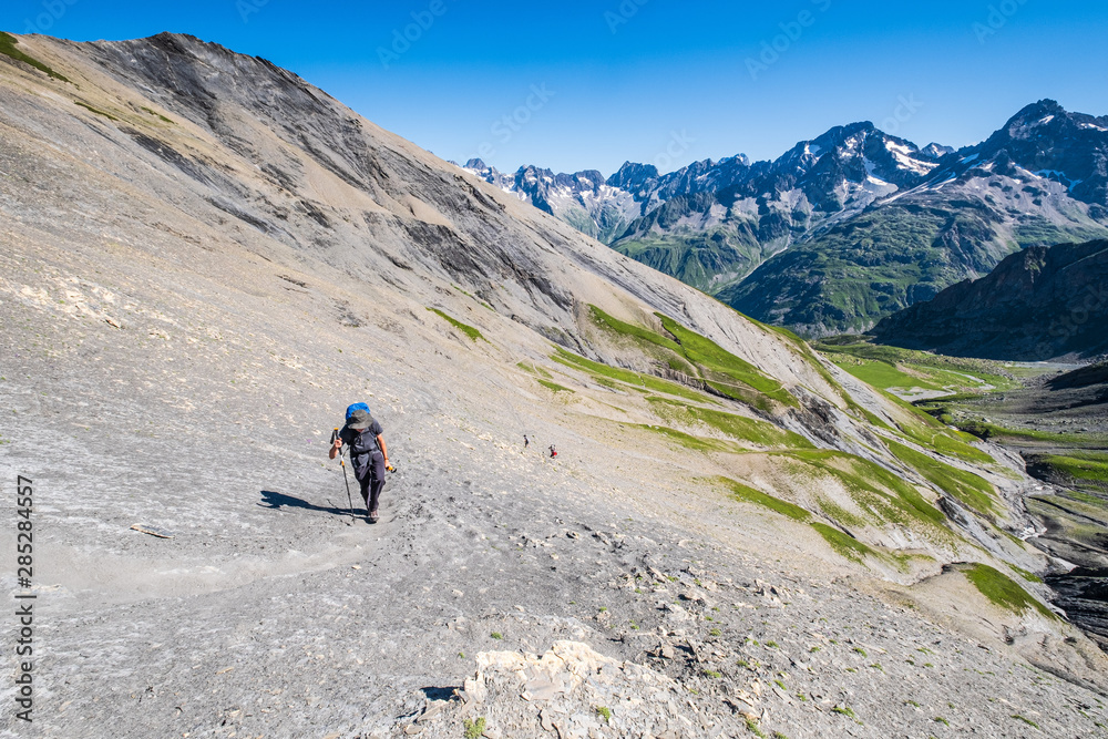 Obraz premium A hiker slowly ascending the trail toward the Vallonpierre Pass in the Ecrins National Park, French Alps