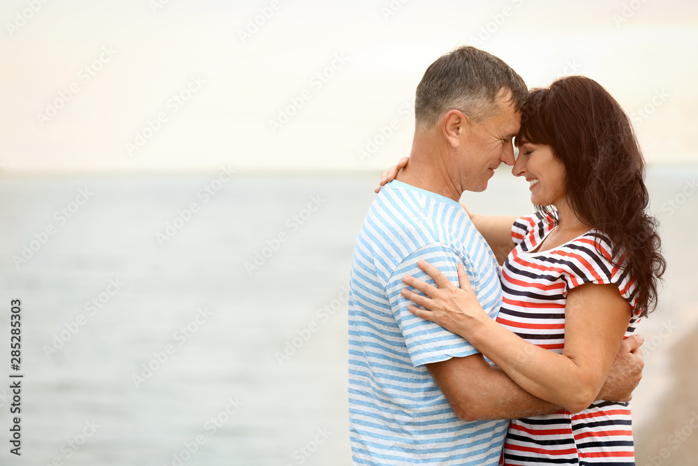 Happy mature couple spending time together on sea beach. Space for text Happy mature couple spending time together on sea beach. Space for text
