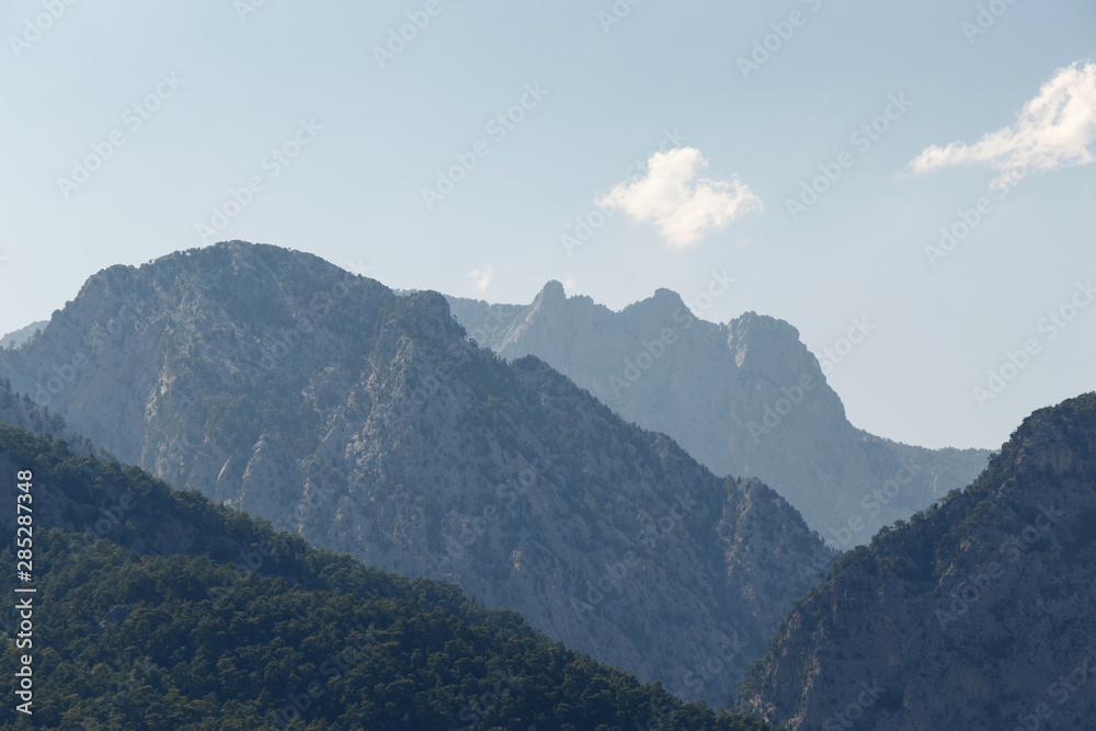 Beautiful landscape in the mountains. Lovely view of the Taurus Mountains against the blue sky and clouds. Soft sunlight falls on the mountain tops. Kemer, Turkey. Postcard view
