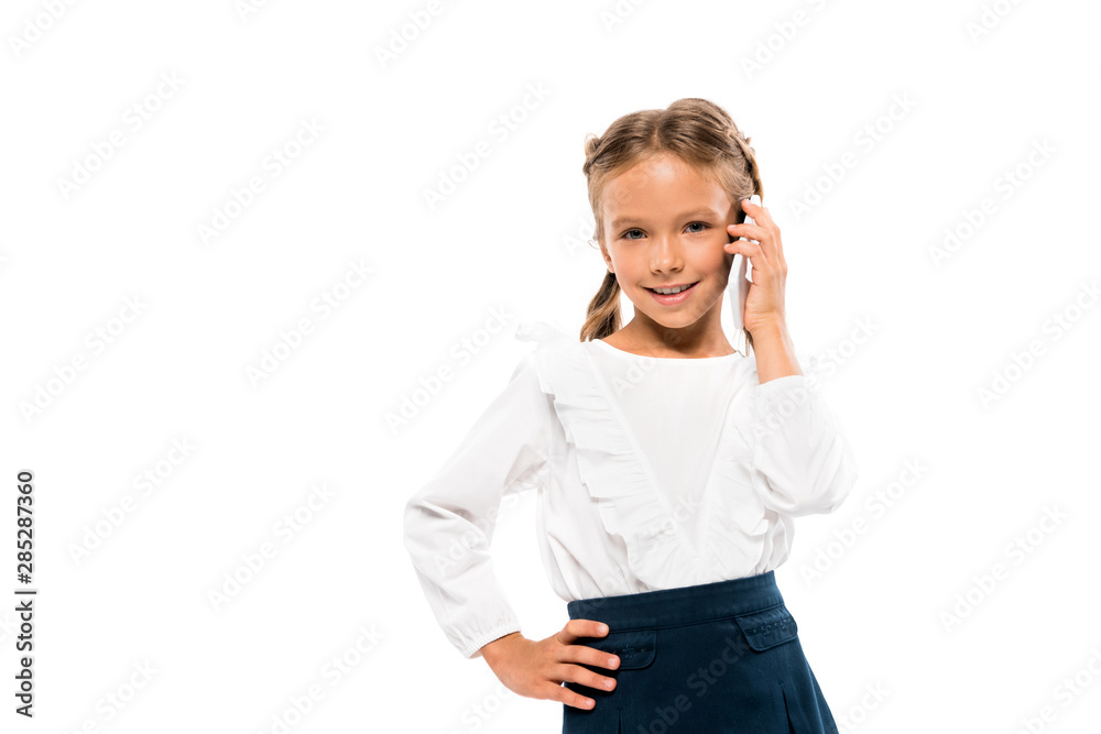 positive kid standing with hand on hip and talking on smartphone isolated on white positive kid standing with hand on hip and talking on smartphone isolated on white